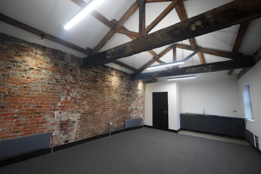 Workspace with exposed brick, timber trusses and fitted kitchenette